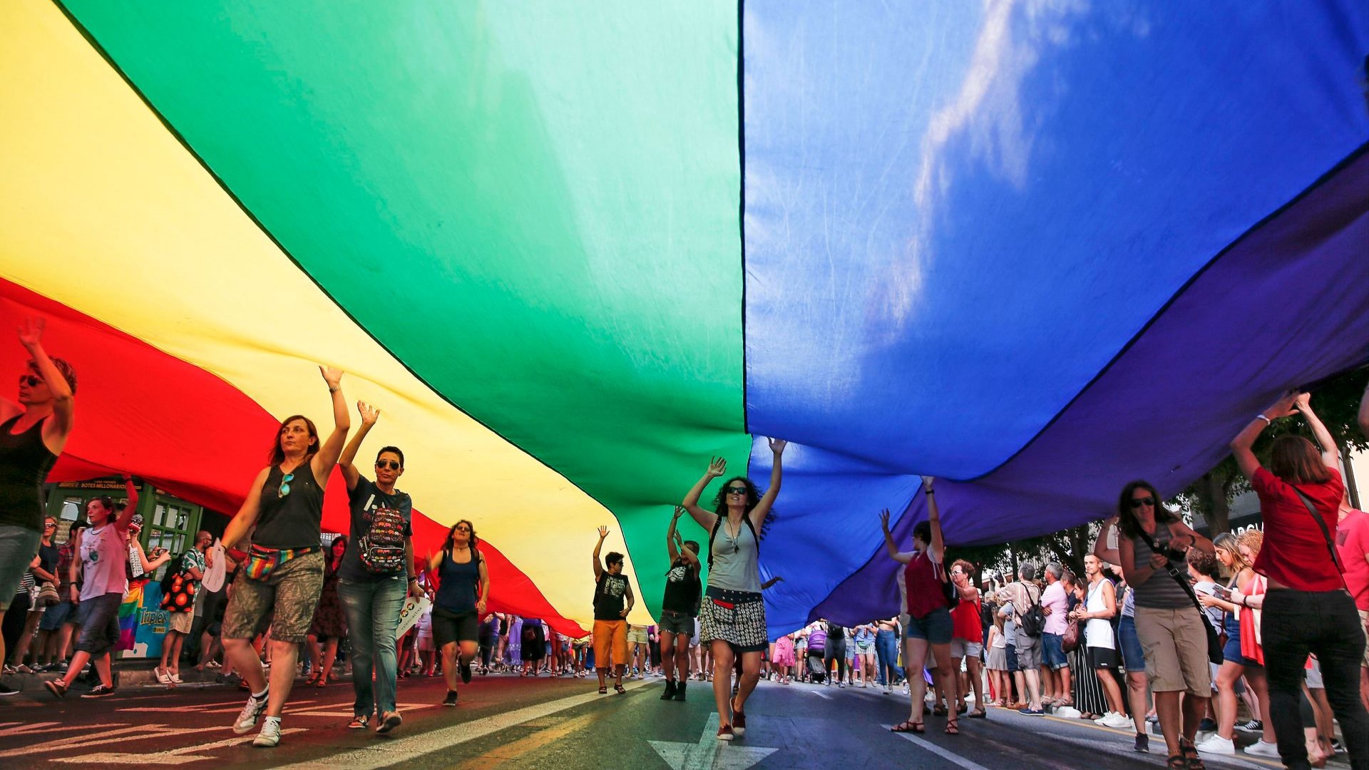 Varias persoas portan unha bandeira xigante do arco da vella durante a manifestación do Orgullo de Valencia, nunha imaxe de arquivo (EFE/Manuel Bruque)