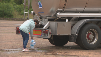 Veciña de Cedeira recollendo auga da cisterna disposta polo Concello