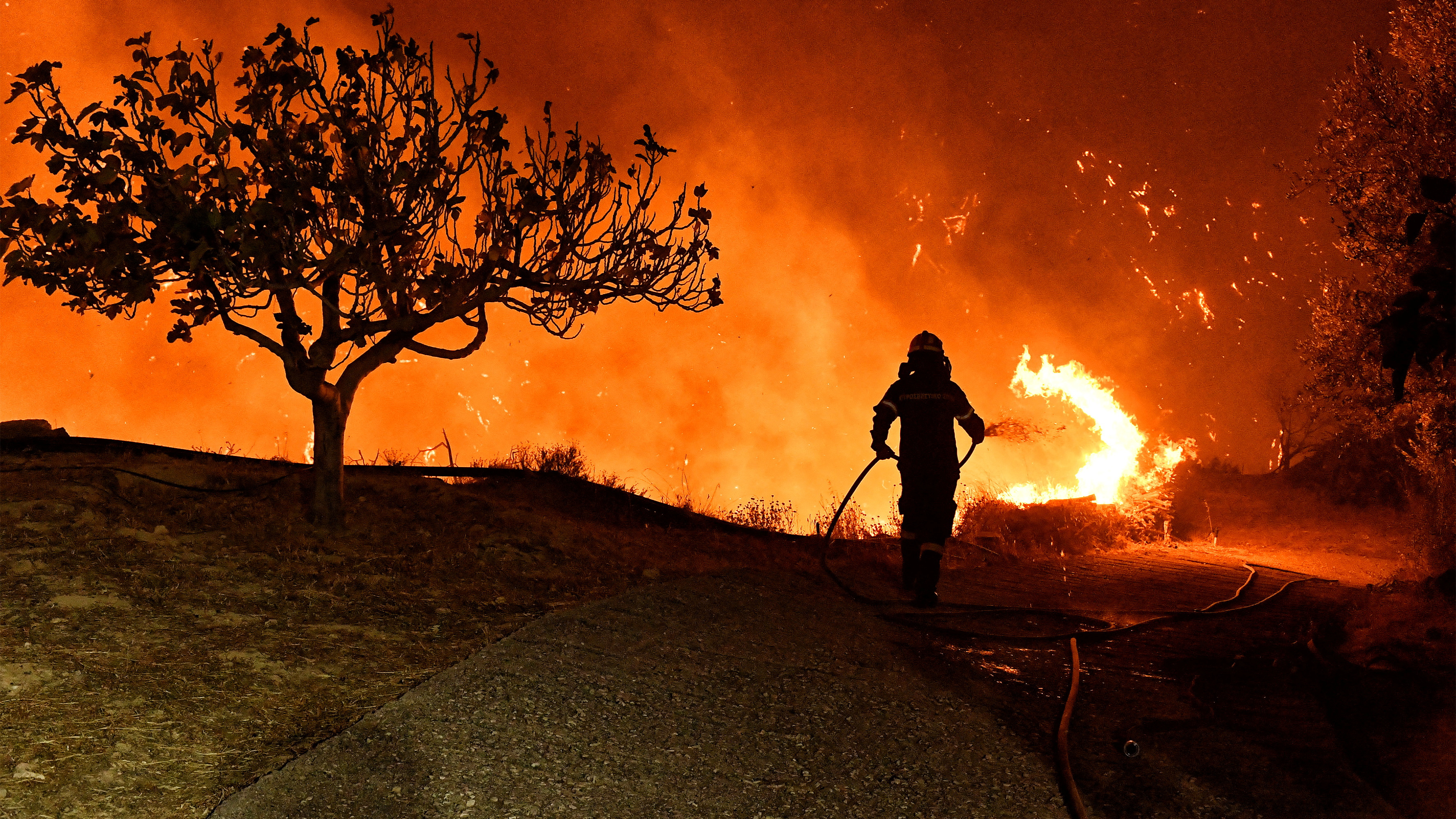 Un bombeiro tenta extinguir o grande incendio declarado na rexión de Corintia (Vassilis Psomas / Reuters)