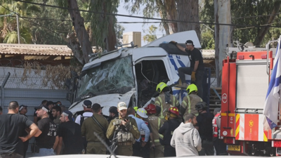 A policía e os bombeiros inspeccionan o camión que bateu contra un autobús en Tel Aviv