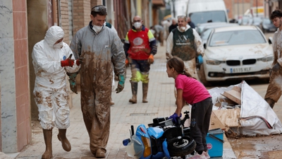 Dous voluntarios saúdan unha nena na Torre, devastada pola DINA. EFE/Manuel Bruque